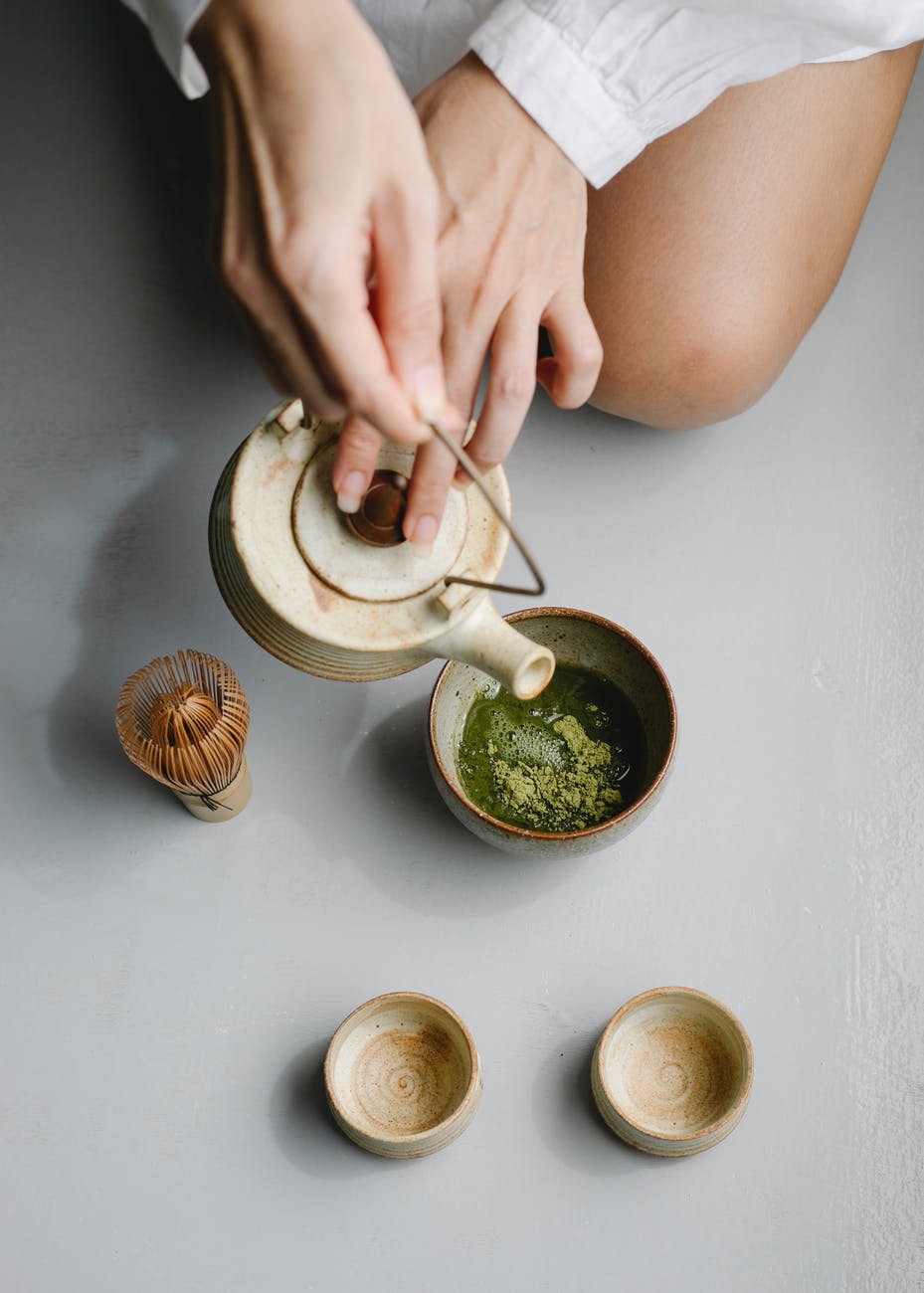 woman pouring herbal tea from teapot for tea ceremony