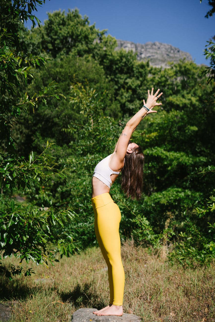 woman in white tank top raising her hands